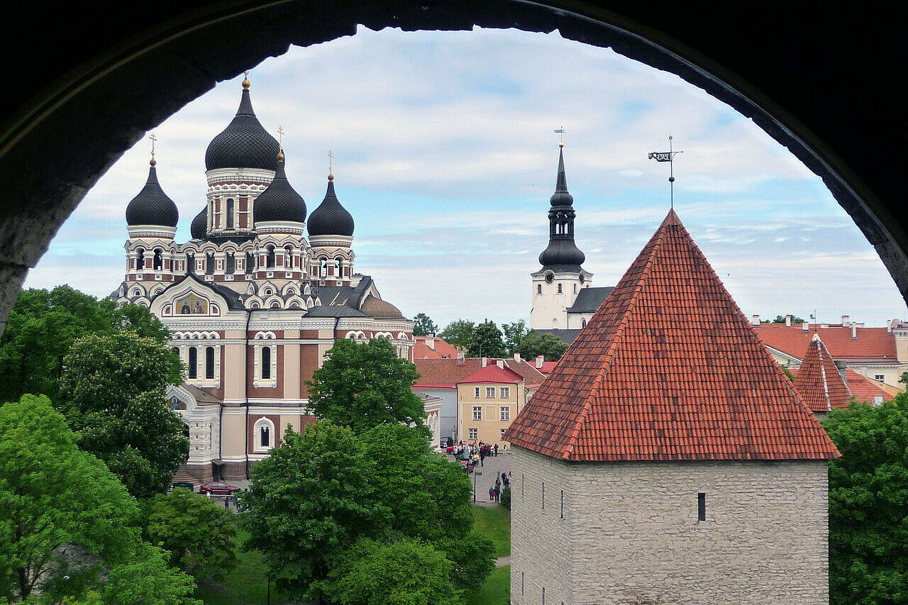 Blick durch ein Rundbogenfenster auf eine Kirche
