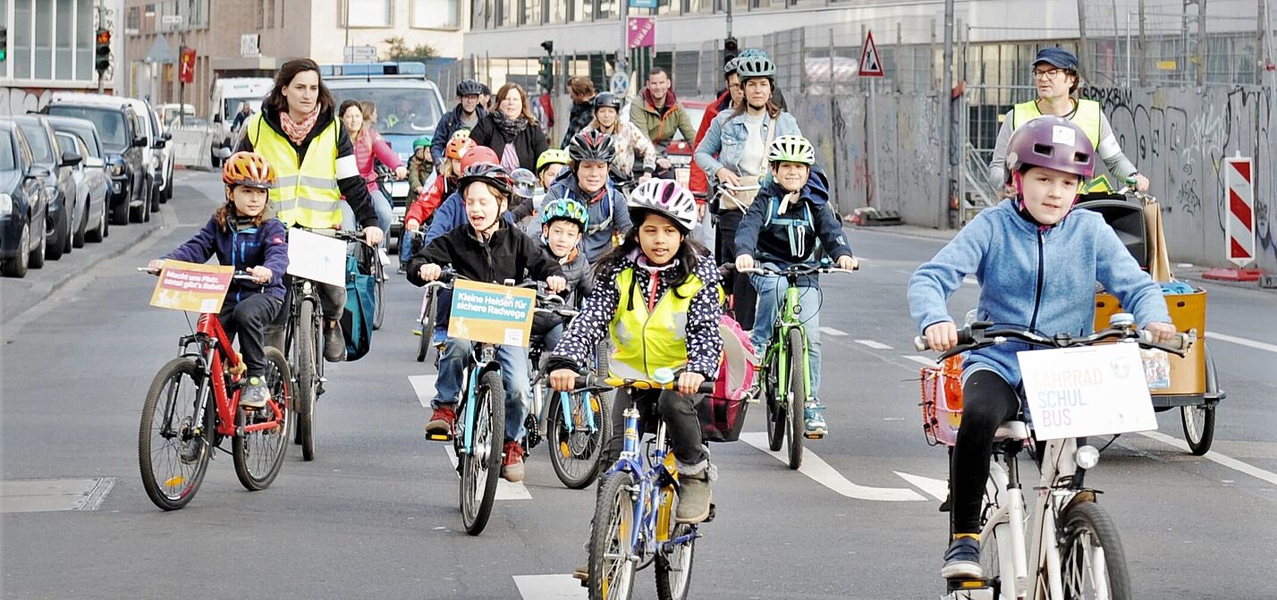 Beim Fahrradbus fahren Kinder und Eltern in der Gruppe auf der Straße. Beim Fahrradbus fahren Kinder und Eltern in der Gruppe auf der Straße.